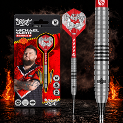 Shot Michael Smith Series II Turbo Point Steeldart 90% – Verpackung, senkrechter Dart und Barrel-Detail vor dunklem Rauchhintergrund